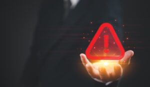 A businessman holding a digital triangle warning sign