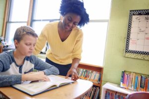 A teacher works on-on-one with a young student reading a book