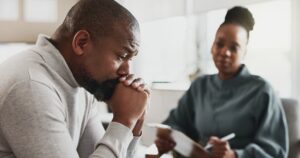 An African-American female counselor works with a grief-stricken African-American male client